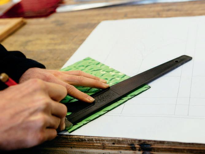 Using the square as a guide to cut the glass.