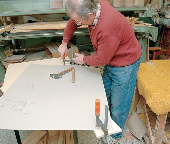 The full-size drawing clamped to a sheet of mdf is used to transfer the proﬁle of the legs directly